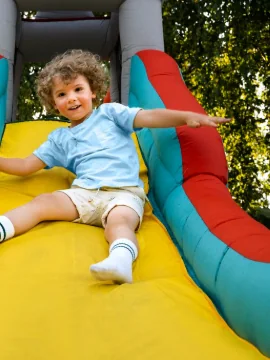 Niño bajando feliz por la resbaladilla de un brincolín